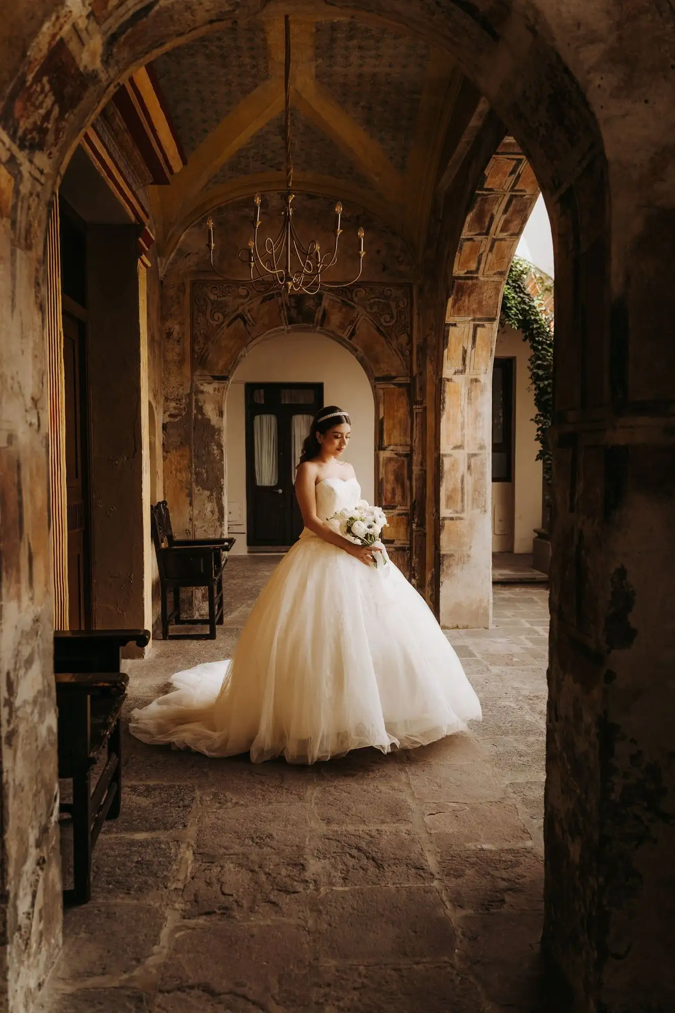 Strapless ball gown wedding dress with a sweetheart neckline in a sunlit stone courtyard