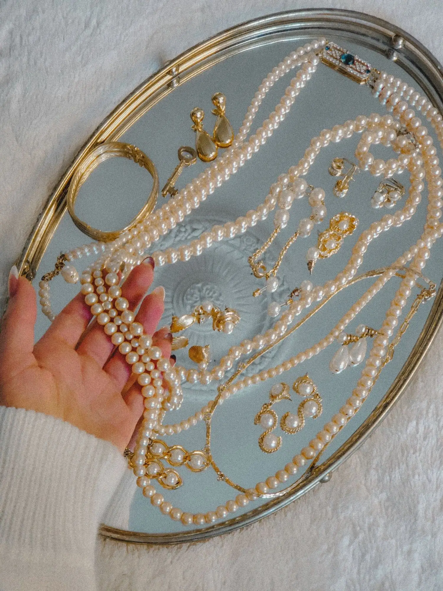 Collection of pearl necklaces, earrings, and bracelets displayed on a mirrored tray