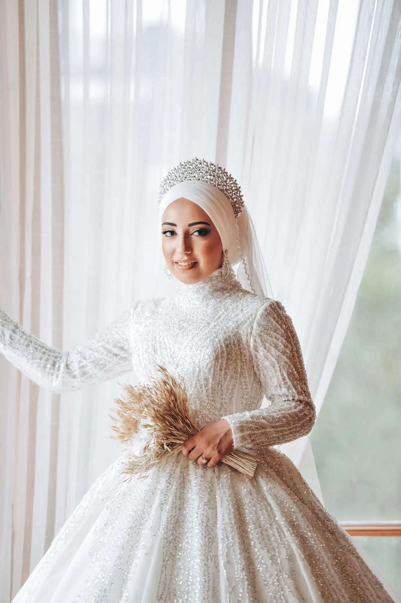 Sequined high-neck wedding gown with long sleeves, worn with a beaded hijab and headpiece