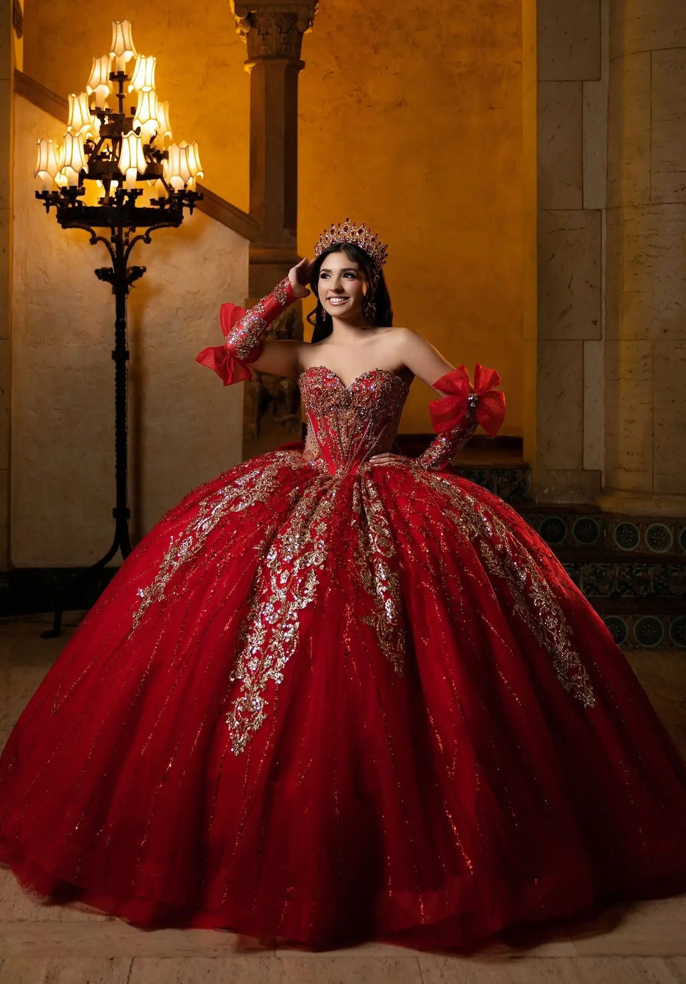 Morilee red quinceañera ball gown with gold lace appliqué and long gloves with bow accents