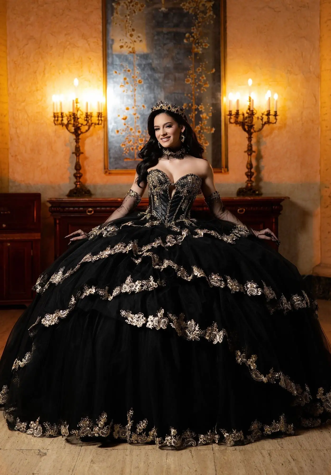 Morilee black quinceañera ball gown with gold lace appliqué and a corset bodice