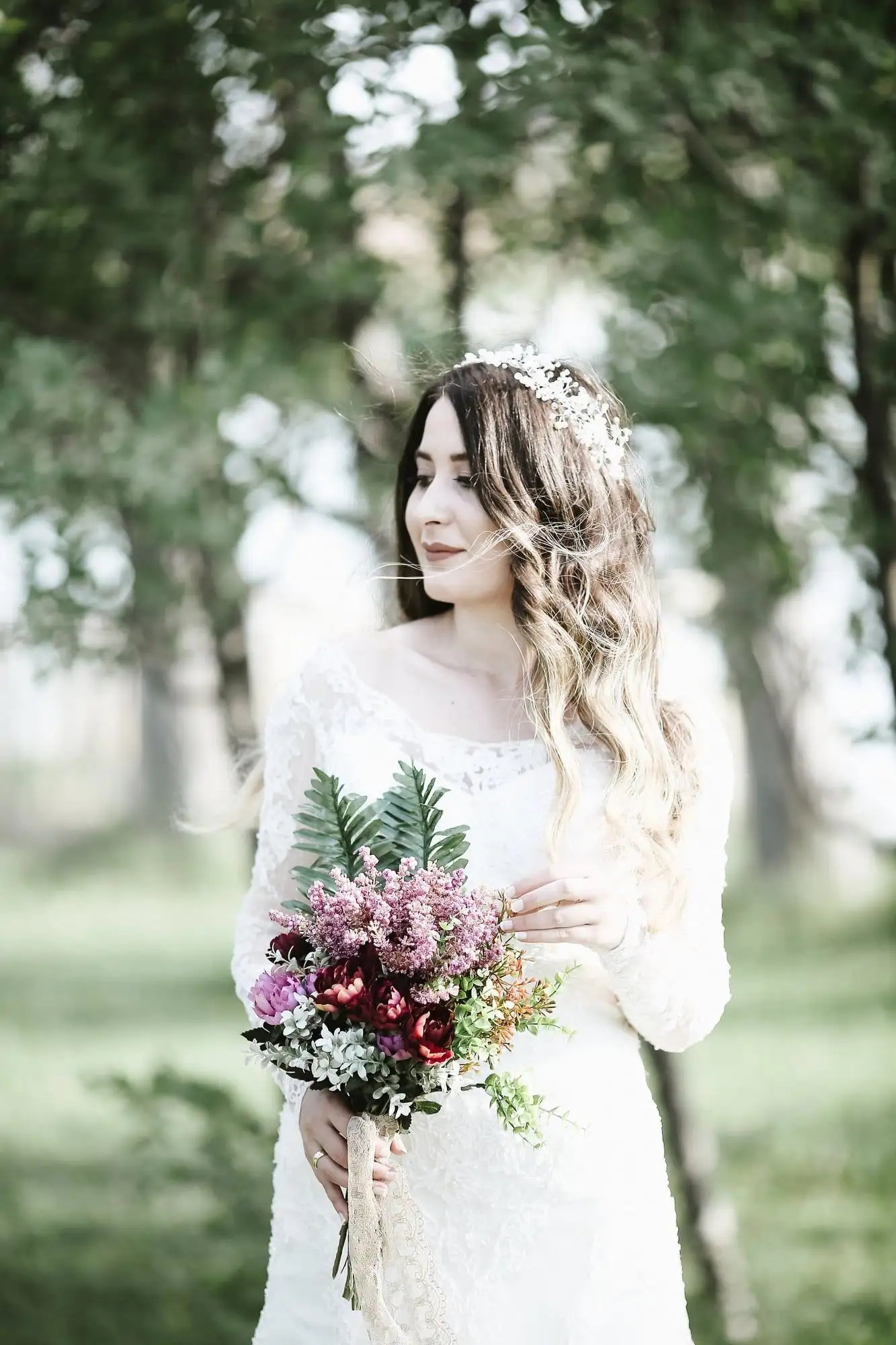 Lace wedding gown with long sleeves, worn with a baby's-breath flower crown in a garden