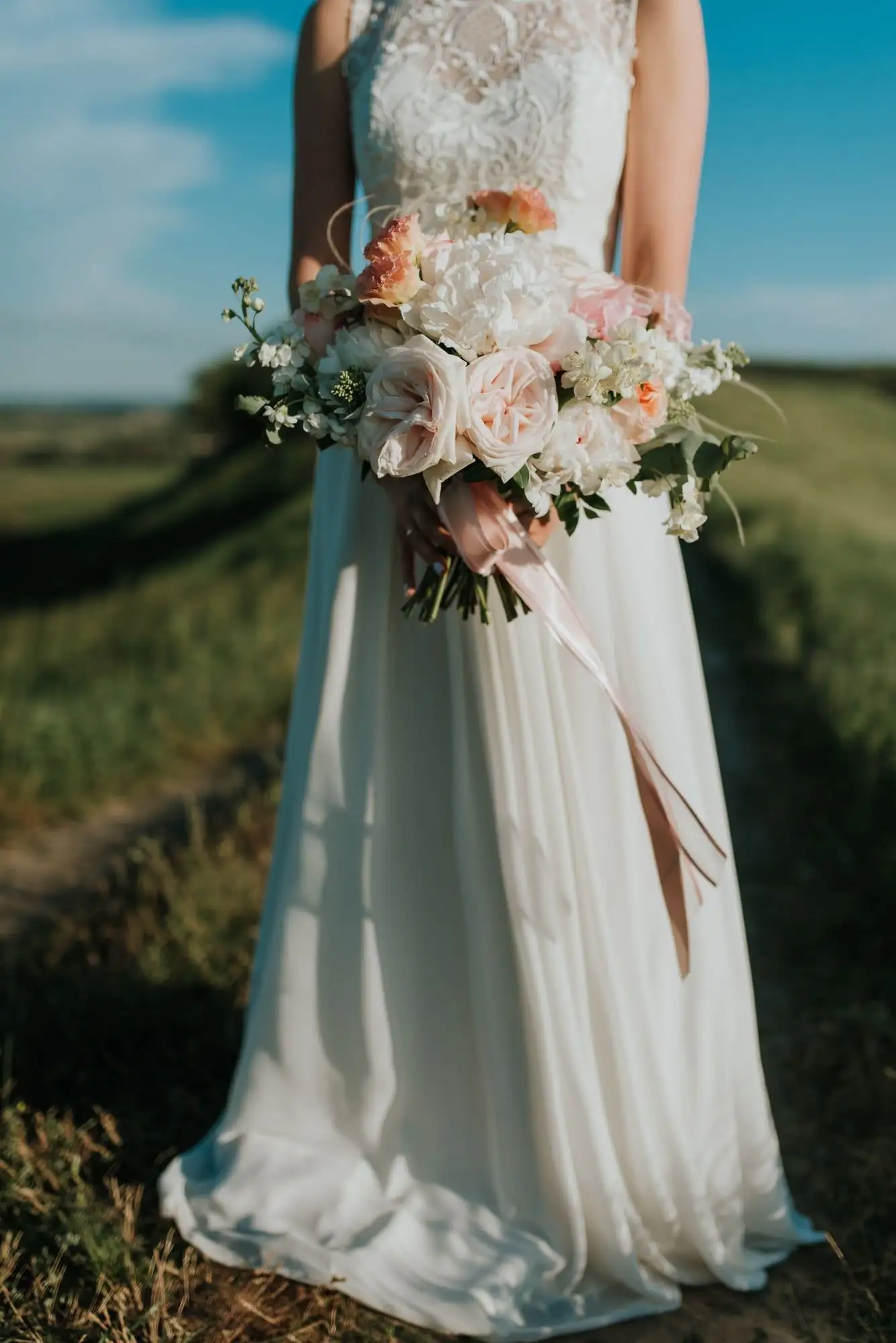 Lace-bodice wedding gown with a flowing A-line skirt, paired with a blush and white bouquet